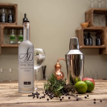 Aval Dor Potato Vodka on a wooden bar top with a gin and tonic glass, shaker and ingredients - square crop