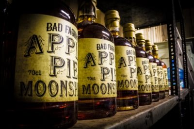 Apple Pie Moonshine bottles lined up on a metal shelf in Exeter Distillery
