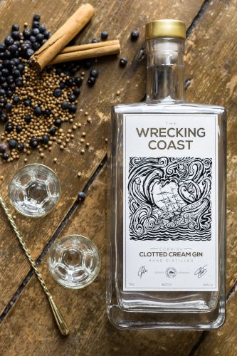 Birds Eye view of Wrecking Coast Clotted Cream Gin bottle on a wooden table with juniper and spoon