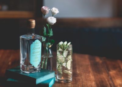 Granny Garbutt's Gin on a small stack of books on a dark table next to a drink