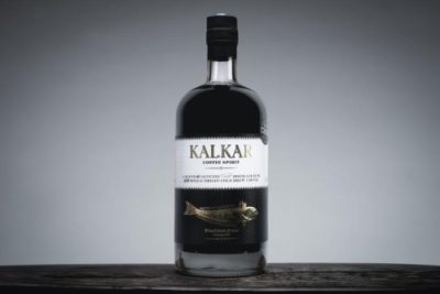 Kalkar Coffee Liqueur bottle on a dark wooden table with a grey background