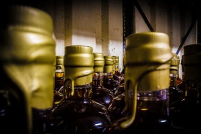 Many gold tops of the Bad Fagins Apple Pie Moonshine bottles on a metal shelf in Exeter distillery