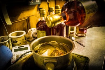 The top of a Bad Fagins Apple Pie Moonshine bottle being dipped into gold wax