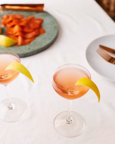 Salcombe gin 'Rose Sainte Marie' cocktail in a coupe glass on white table cloth with some food on a plate