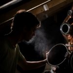Man looking into a steaming still at Capreolus Distillery