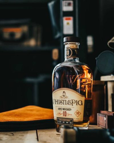 WhistlePig Rye Whiskey bottle on a wooden table in a dark room