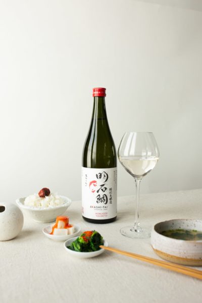 Akashi-Tai Honjozo Tokubetshu Sake bottle on a white table cloth with small Japanese food bowls and glass of sake