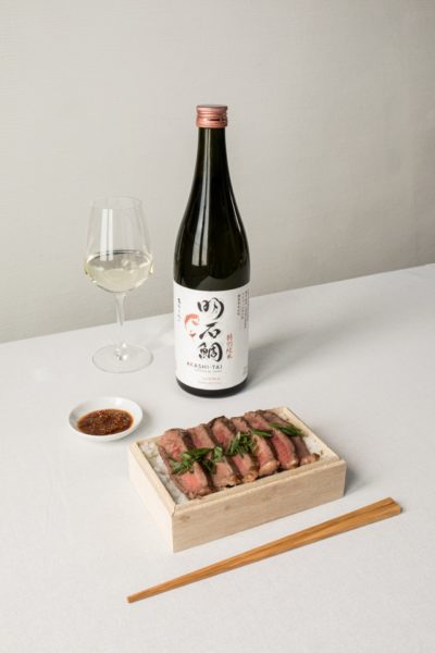 Junmai Tokubetsu Sake bottle on a white table cloth served next to Wagyu steak